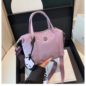 Détail du sac dumpling en nylon lilas avec breloque panda et bandoulière large