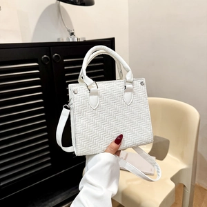 White woven texture tote bag with round handles and crossbody strap in a modern room
