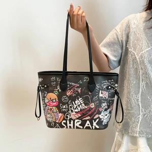 Black tote bag with colorful street graffiti and teddy bear pattern held in hand