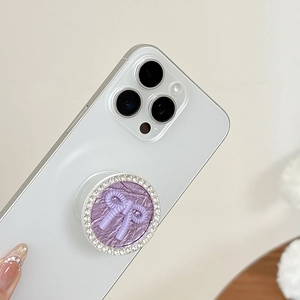 Detail of purple bow phone grip with sparkling rhinestones on a white smartphone