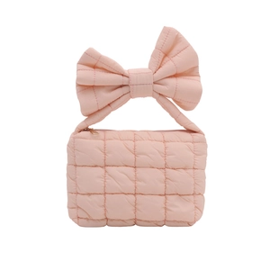 Pink quilted handbag with a large bow handle and soft padded texture for women
