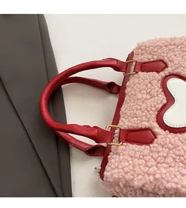 Detail of pink faux shearling bag with red leather handles and gold metal hardware