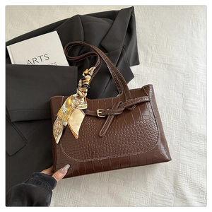 Detail of dark brown croc-effect tote bag with chic silk scarf and metal strap buckle