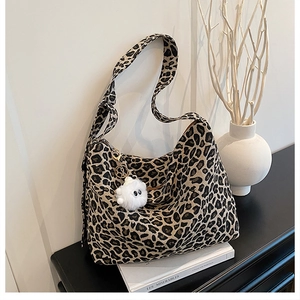 Close-up of leopard print canvas tote bag with a white plush monster pendant detail