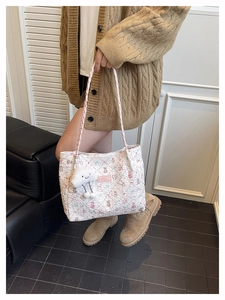 Detail of white quilted tote bag with floral bear patterns and a soft cloud charm