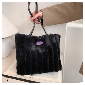 Détail d'un sac cabas en peluche noire avec rayures verticales et étiquette logo