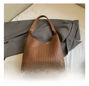 Dettaglio borsa hobo in pelle intrecciata marrone con tracolla liscia e cerniera zip