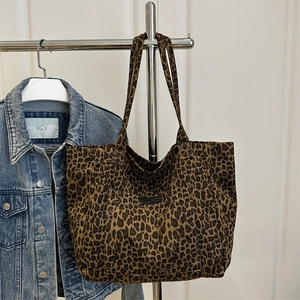 Modern leopard print canvas tote bag with front pocket shown against denim jacket