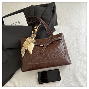 Brown crocodile pattern tote bag with white stitching and decorative silk scarf detail