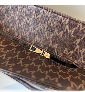 Detail shot of smooth gold zipper and monogram jacquard fabric on the brown tote bag