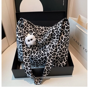 Detail of leopard print canvas tote bag with plush monster charm in a gift box