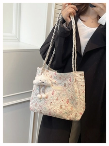 Detail of floral underarm bag with teddy bear pattern and braided straps and cloud charm