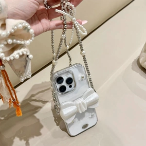 Détail de la coque iPhone 16 Pro avec nœud 3D pailleté et bandoulière en perles