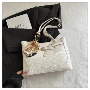 Detailed shot of white crocodile embossed tote with decorative gold silk scarf on handle