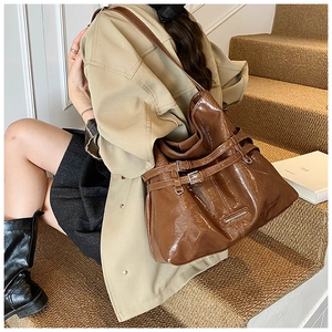 Dettaglio di una borsa a secchiello in pelle lucida marrone con fibbie argento vintage