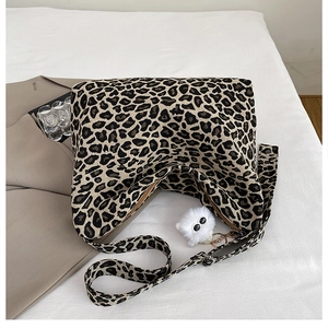 Detail of leopard print tote bag with white plush kitten charm and adjustable strap
