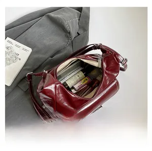 Deep red messenger bag detail showing spacious interior with cosmetics and phone