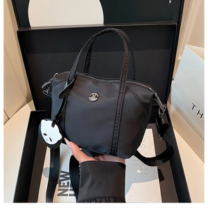 Detail of black nylon crossbody bag with panda charm and round metal logo on gift box