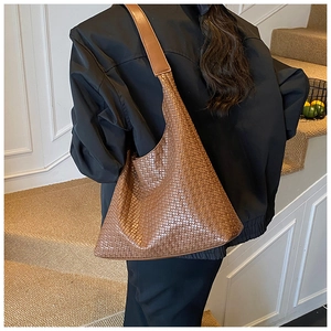 Dettaglio della grande borsa hobo intrecciata marrone con trama in pelle sulla spalla