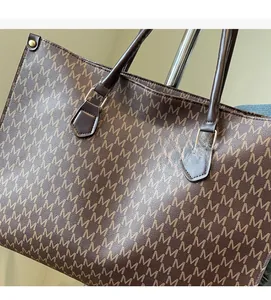 Detail of vintage brown tote bag showing M-pattern texture and reinforced leather handles