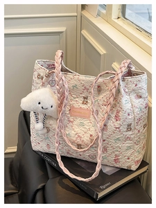 Close-up of quilted floral tote bag with cartoon patterns and pink braided straps