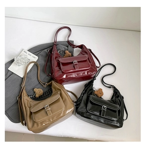 Three glossy leather shoulder bags in burgundy, khaki, and black with front buckle pocket