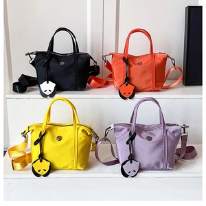 Selection of colorful nylon dumpling bags in black, orange, yellow, and purple with panda charms