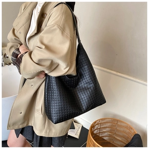 Dettaglio della trama della borsa hobo intrecciata nera indossata su un trench beige