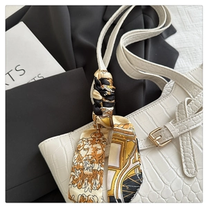 Detail of white crocodile texture shoulder bag with silk scarf and gold metal buckle
