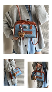 Détail du porte-documents en denim bleu et cuir marron avec breloque ours en peluche