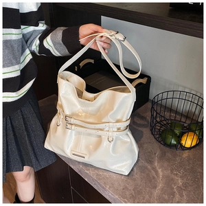 Dettaglio di una borsa a secchiello in pelle lucida crema con fibbie e finiture argentate