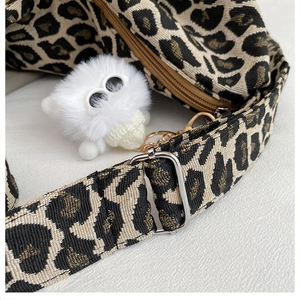 Detail of leopard print canvas bag featuring silver buckle and white plush charm