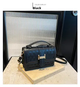 Detail of black rectangular handbag with geometric texture and gold buckle on art books