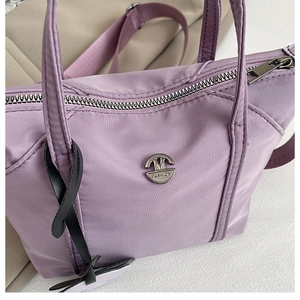Détail du sac en nylon lavande avec logo M-Fashion en métal argenté et fermeture éclair fine