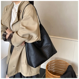 Grande borsa tote nera intrecciata sulla spalla della modella per l'uso quotidiano di stile