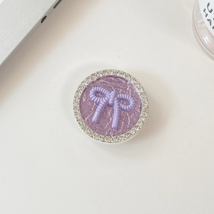 Close-up of circular phone grip with purple bow and sparkling rhinestone frame