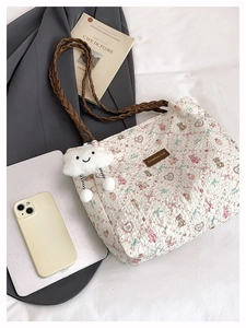 Detail of white pleated tote bag featuring bear prints and a cloud plush charm