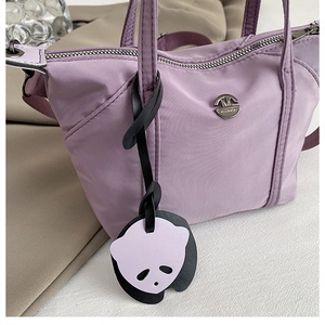 Détail du sac violet en nylon avec charme panda et emblème logo métallique rond