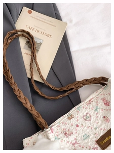 Dettaglio della borsa tote crema plissettata con motivi floreali e manici marroni