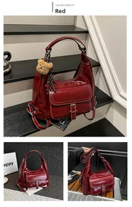 Detail of red patent leather tote bag with teddy charm and striped scarf decoration