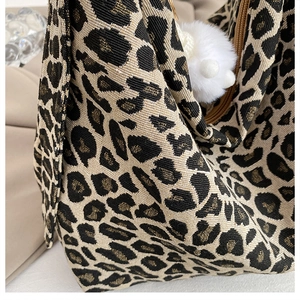 Detail of leopard print jacquard canvas with metallic threads and white fur pom-pom charm
