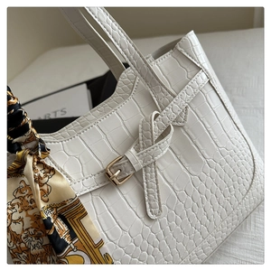 Detail of white crocodile pattern tote bag with vintage silk scarf and gold buckle