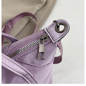 Détail du sac en nylon lavande montrant le zip métallique et les coutures de l'anse