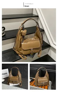Brown glossy tote bag with flap buckle pocket and plush bear charm in side view