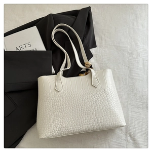 Detailed view of white crocodile pattern tote bag featuring a decorative silk scarf handle