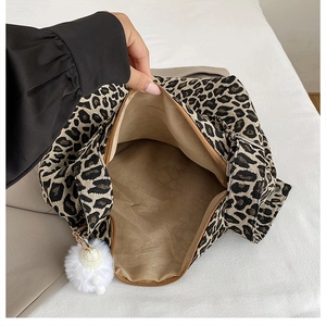 Detailed view of leopard print tote bag interior with zipper closure and plush charm