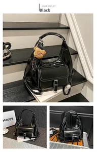 Detail of black glossy vintage backpack with white stitching and bear charm