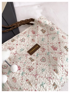 Dettaglio borsa tote in seersucker con stampe animali, manico in pelle e pompon morbido