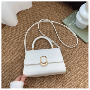 Detailed close-up of white crocodile pattern handbag with gold clasp on textured background