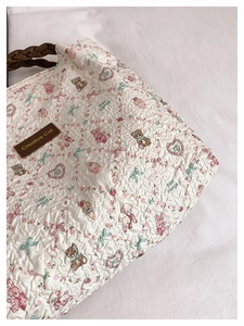 Detail of white pleated tote bag with cute animal prints and woven handle texture